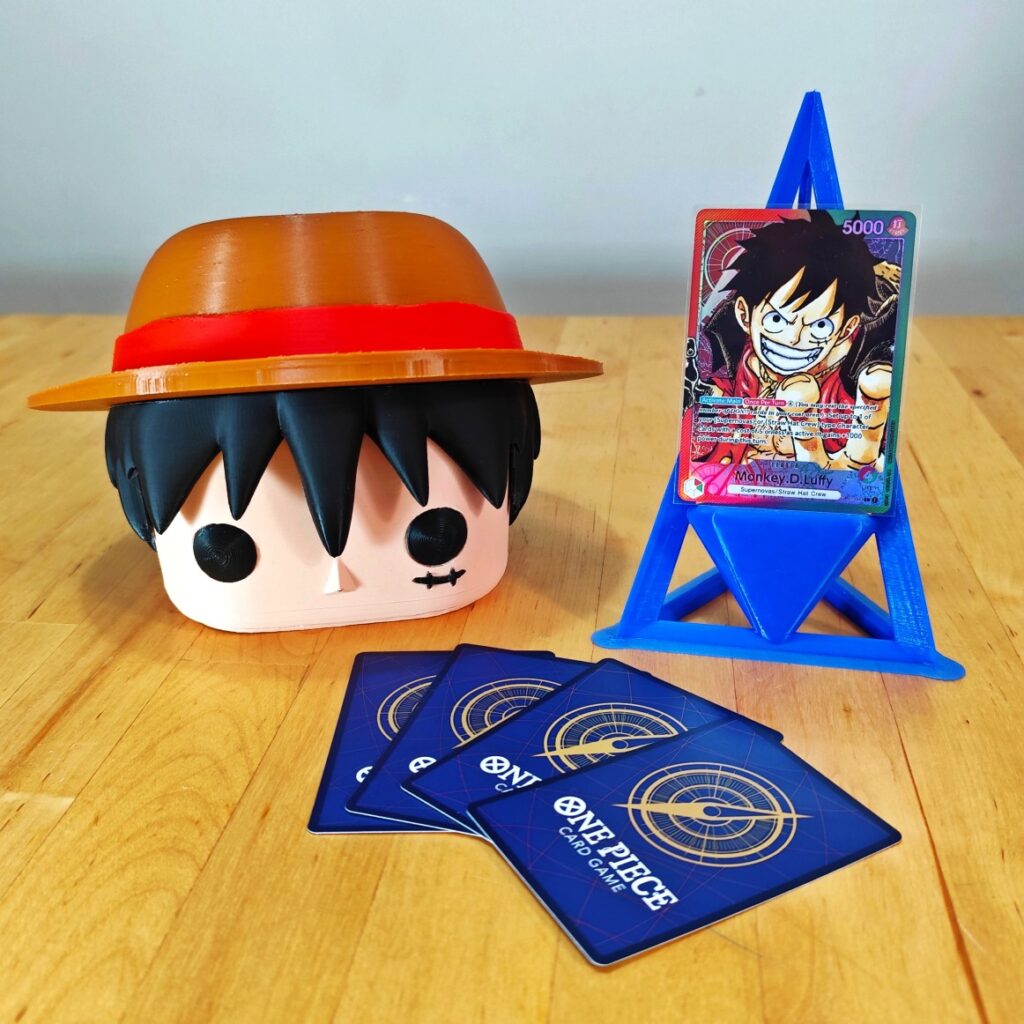 Deckbox Funko Pop de Monkey D. Luffy junto a cartas de One Piece TCG y un soporte azul. Diseño coleccionable inspirado en el protagonista de One Piece.