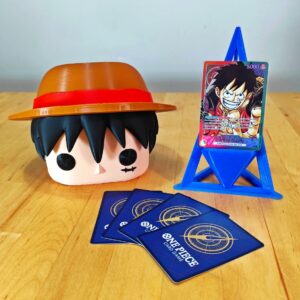 Deckbox Funko Pop de Monkey D. Luffy junto a cartas de One Piece TCG y un soporte azul. Diseño coleccionable inspirado en el protagonista de One Piece.