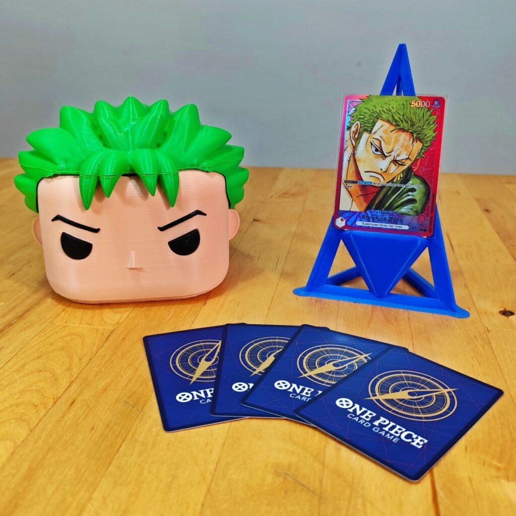 Deckbox Funko Pop Zoro con cartas de One Piece TCG y soporte para exhibición.