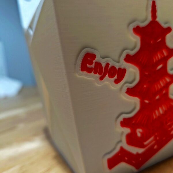 Detalle lateral de la deckbox con el mensaje "Enjoy" en relieve