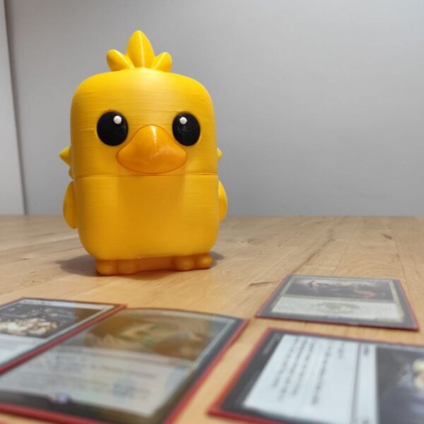 Vista frontal de la deckbox Chocobo Baby mostrando el compartimento abierto con las cartas en su interior.
