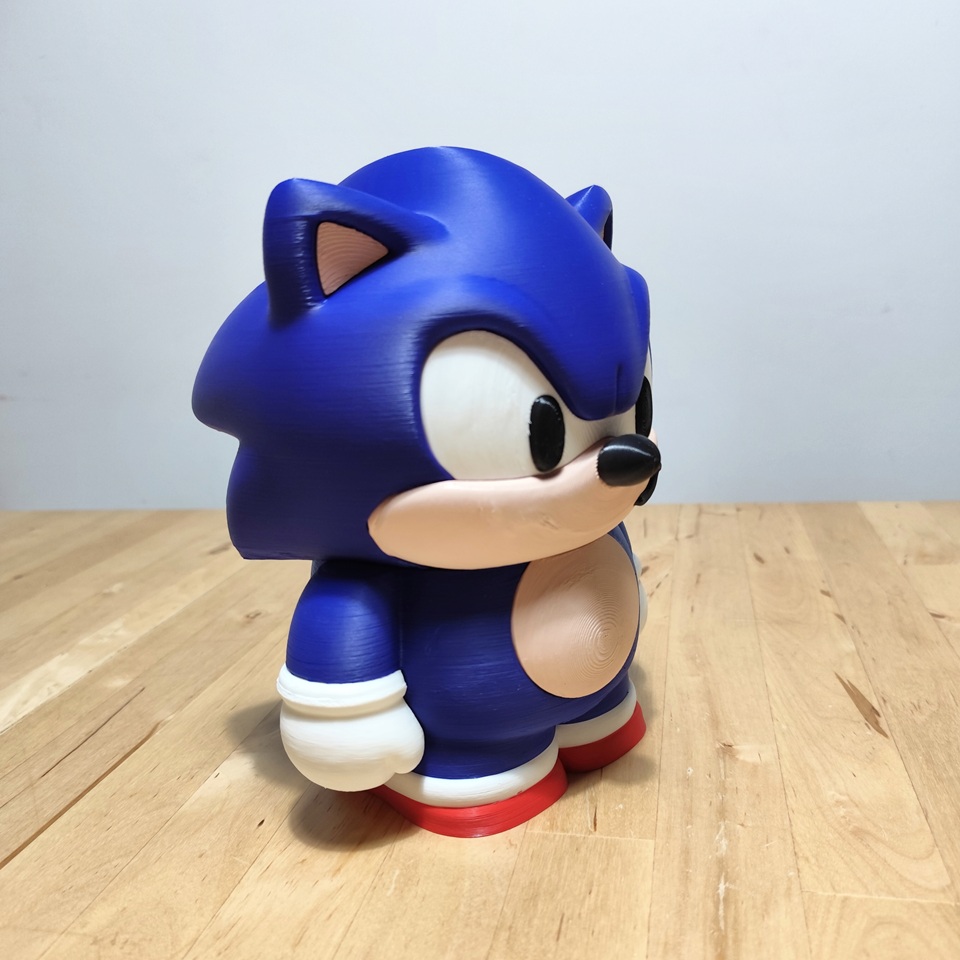 Deckbox Sonic The Hedgehog vista frontal, lateral y posterior, mostrando el diseño de la tapa, cuerpo y base, con cartas de juego de TCG.